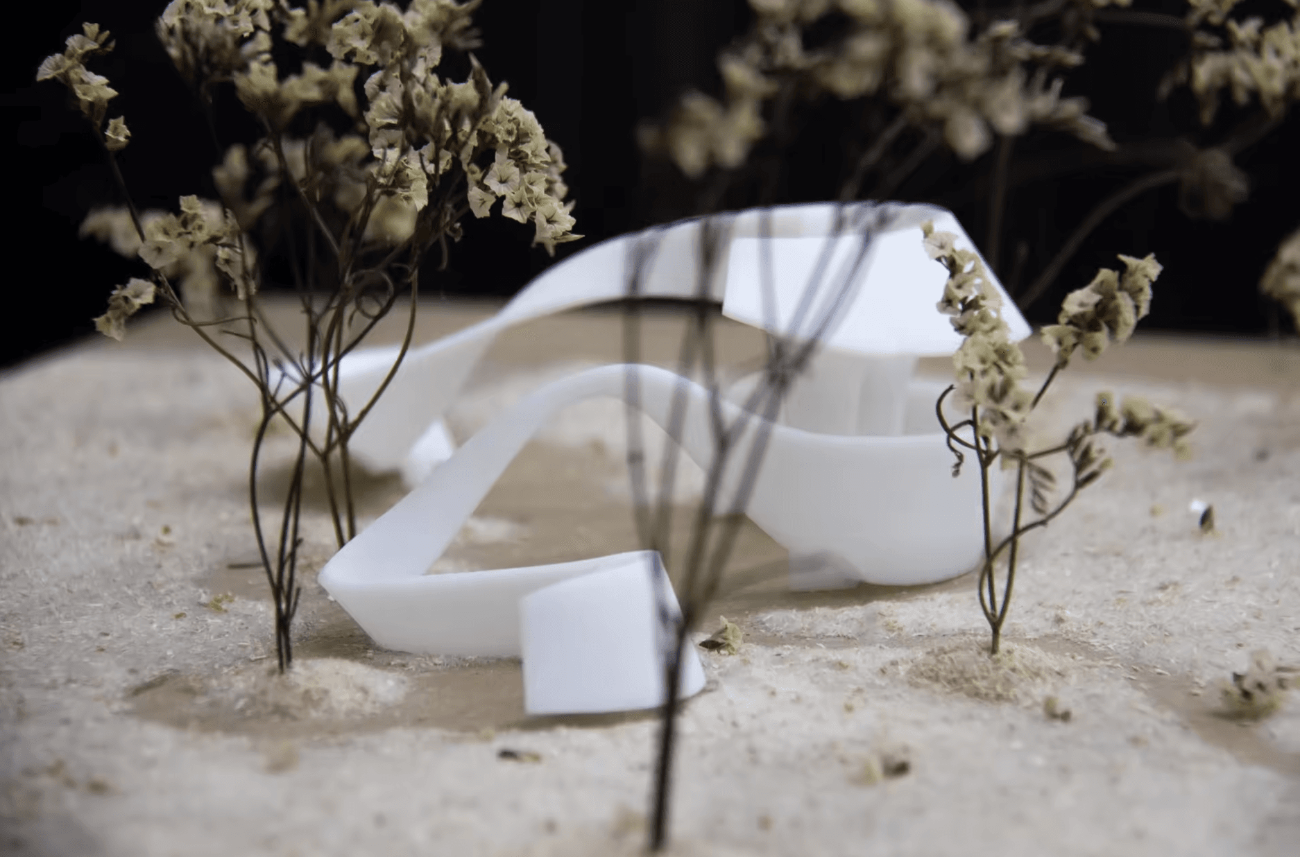 White study model of a continuous curved strip wrapping around small trees on a landscape base