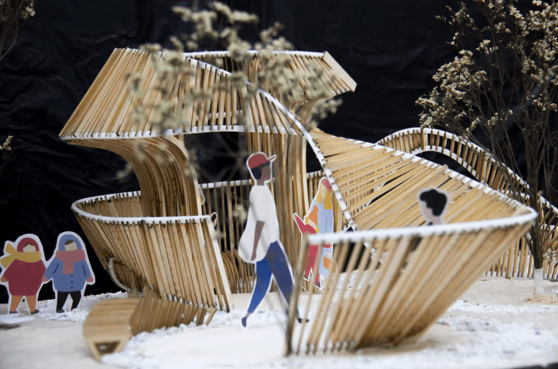 Close view of the physical model with figures beside curved slatted edges, open passages, and trees