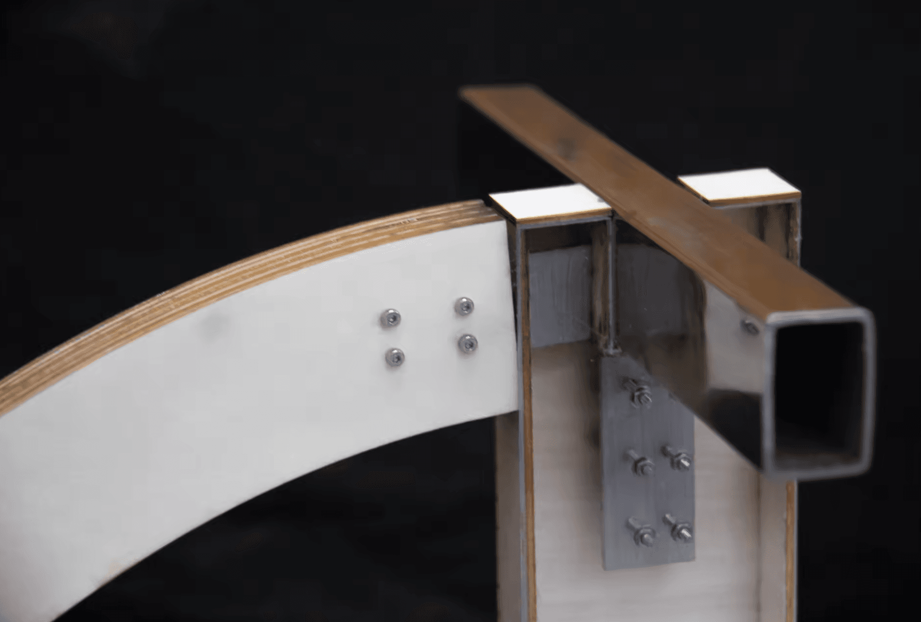 Close-up of a connection model with a curved layered member, metal plates, bolts, and a vertical support