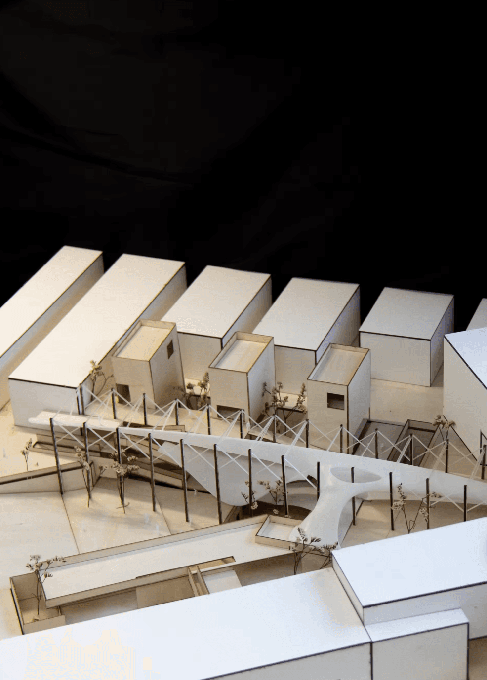 Physical model showing a line of framed curved volumes in front of the taller existing urban fabric
